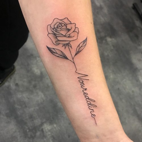 Roos met naam fineline tattoo op de onderarm