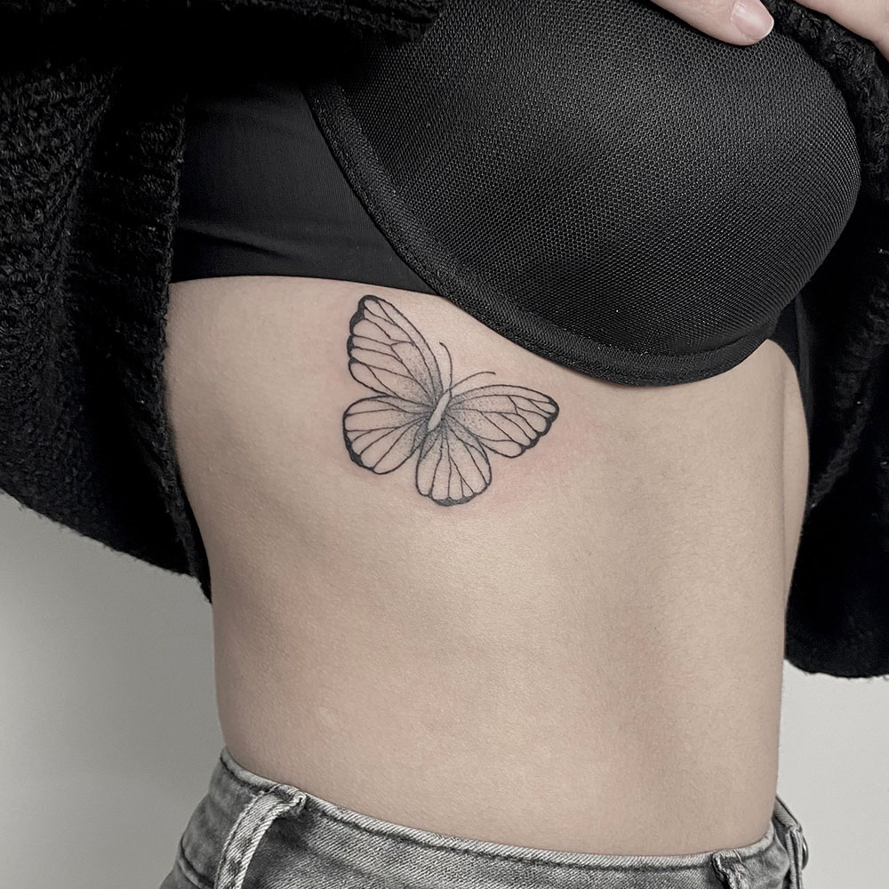 Vrouwelijke tattoo fineline vlinder op ribben