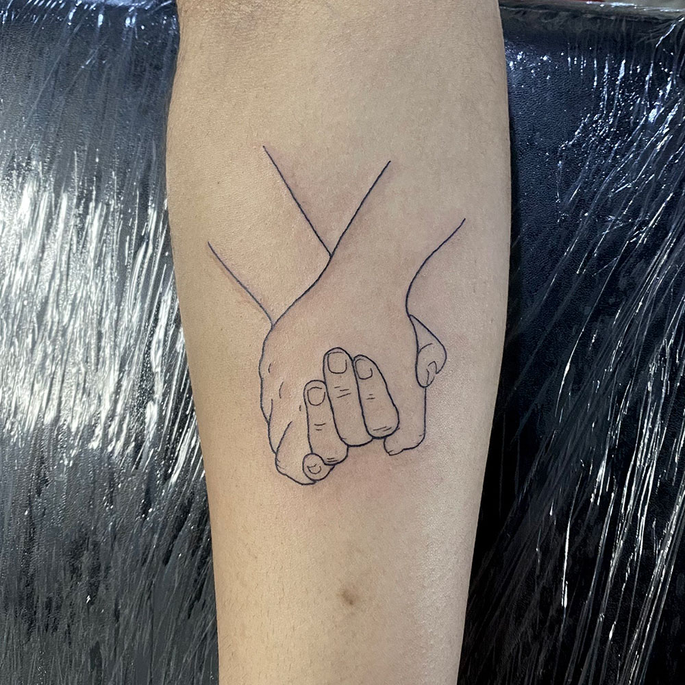 Fineline vasthoudende handen tattoo Danique